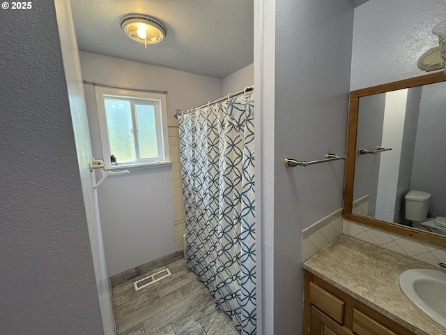 600 NE Oregon Ave, Irrigon, OR 97844 - full bathroom with a textured wall, vanity, toilet, backsplash, and a shower with shower curtain