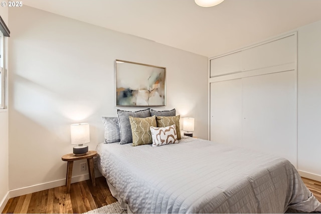 bedroom featuring a closet, baseboards, and wood finished floors