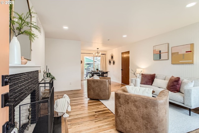 living room featuring recessed lighting, a fireplace, light wood-type flooring, and baseboards