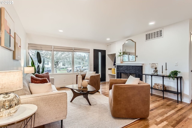 living area featuring light wood finished floors, visible vents, baseboards, recessed lighting, and a fireplace