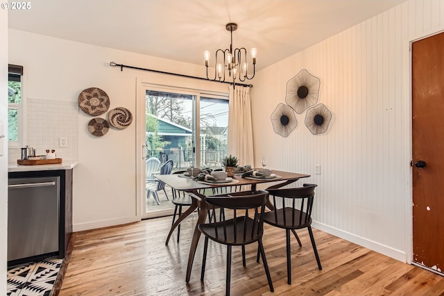 dining space featuring baseboards, light wood finished floors, and a chandelier