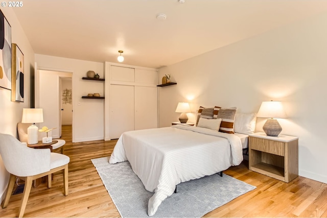 bedroom with a closet, baseboards, and light wood-style flooring