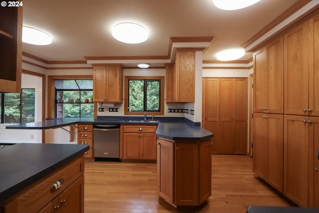 kitchen featuring dark countertops, brown cabinetry, stainless steel dishwasher, and a center island