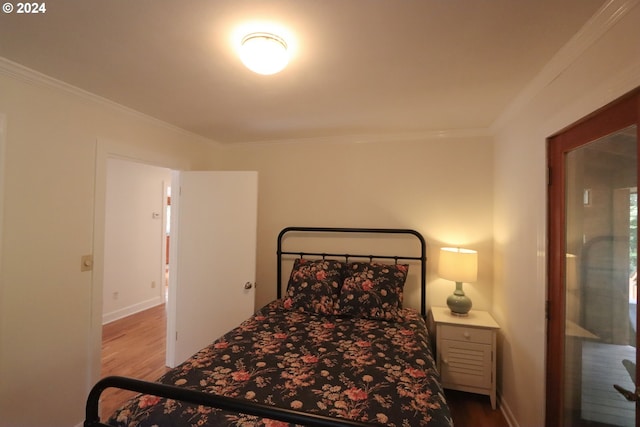 bedroom featuring baseboards, crown molding, and wood finished floors