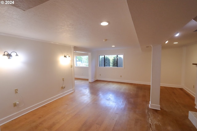 interior space with a textured ceiling, recessed lighting, wood finished floors, and baseboards