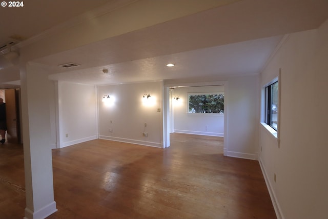 spare room with visible vents, baseboards, wood finished floors, and ornamental molding