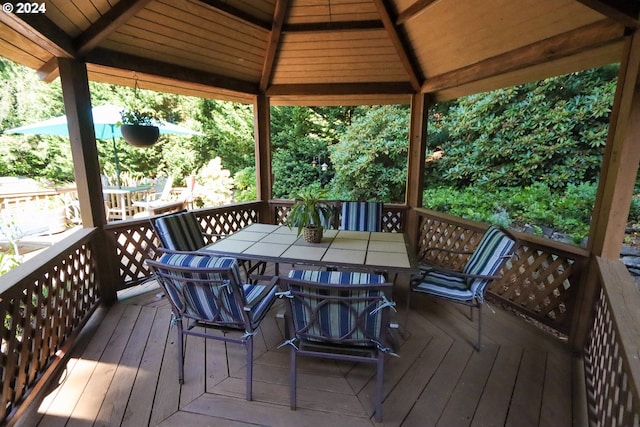 wooden deck featuring outdoor dining area and a gazebo