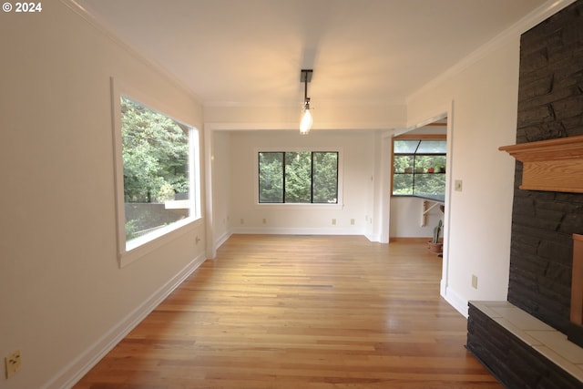 unfurnished living room featuring ornamental molding, light wood-style floors, a fireplace, and baseboards