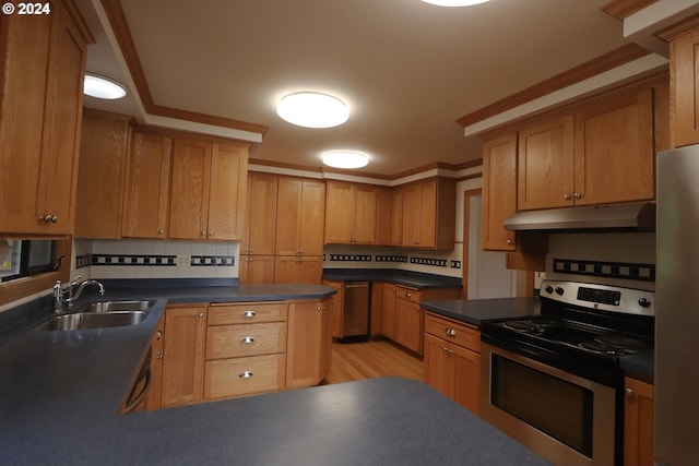 kitchen featuring dark countertops, appliances with stainless steel finishes, brown cabinets, under cabinet range hood, and a sink