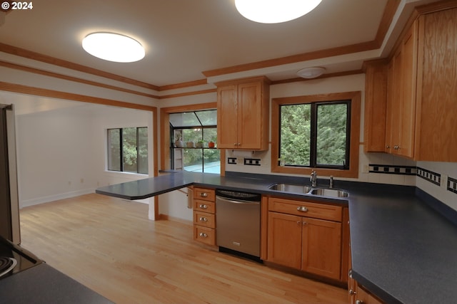 kitchen featuring a sink, ornamental molding, light wood-type flooring, dishwasher, and dark countertops