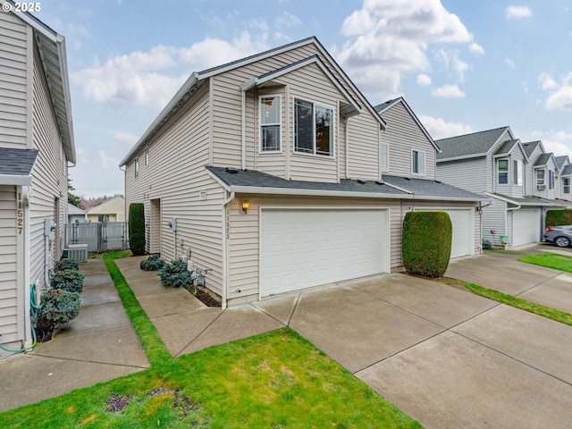 view of front of home with central air condition unit, an attached garage, concrete driveway, and fence