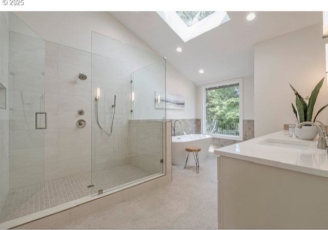 bathroom featuring a freestanding tub, a sink, a shower stall, lofted ceiling with skylight, and tile walls