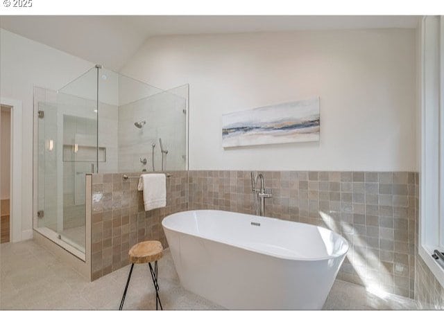 full bath with tile patterned floors, tile walls, a stall shower, and a freestanding bath