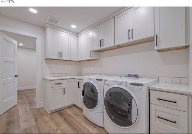 clothes washing area featuring washing machine and clothes dryer, visible vents, recessed lighting, light wood-style flooring, and cabinet space