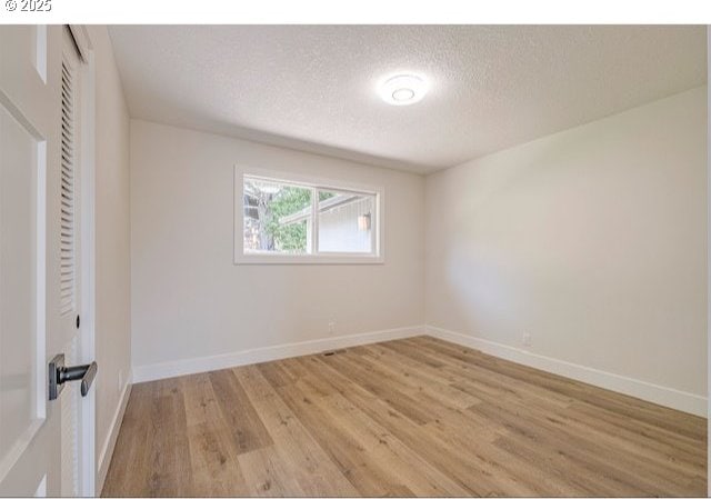 unfurnished bedroom featuring light wood-type flooring, baseboards, and a textured ceiling