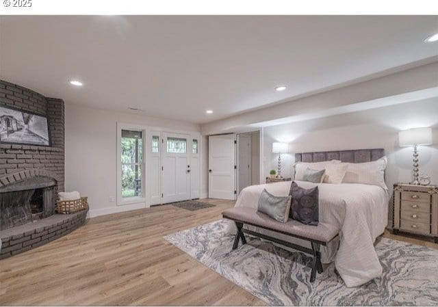 bedroom with recessed lighting, a brick fireplace, baseboards, and wood finished floors