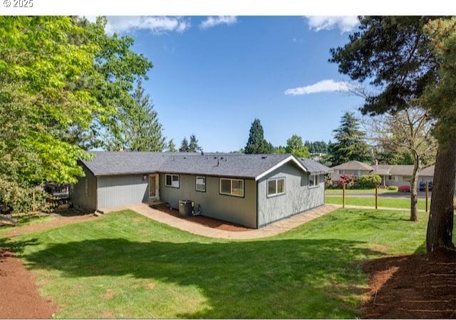 back of house featuring central AC unit and a lawn