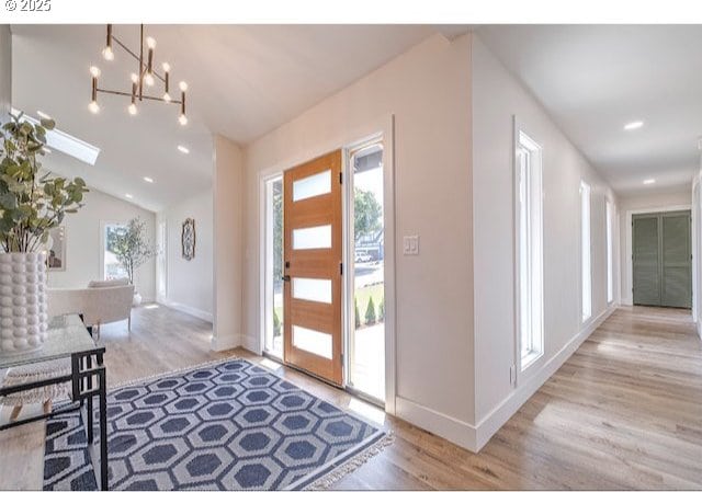 entryway featuring wood finished floors, baseboards, an inviting chandelier, recessed lighting, and vaulted ceiling