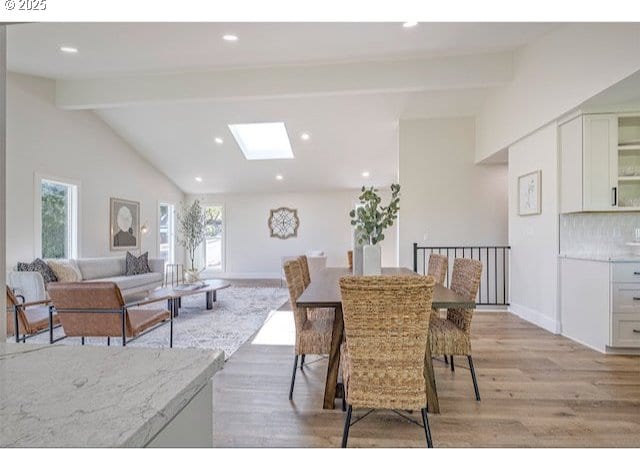 dining area featuring vaulted ceiling with skylight, recessed lighting, light wood-style flooring, and baseboards