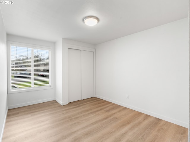 unfurnished bedroom with a closet and light hardwood / wood-style floors