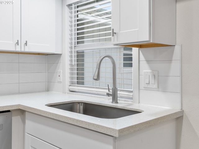 kitchen with light stone countertops, dishwashing machine, decorative backsplash, white cabinetry, and sink