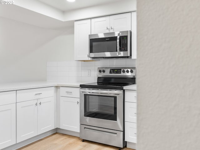 kitchen featuring decorative backsplash, white cabinetry, light hardwood / wood-style flooring, and appliances with stainless steel finishes