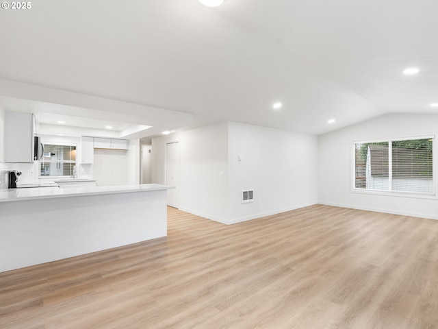 unfurnished living room with lofted ceiling and light wood-type flooring