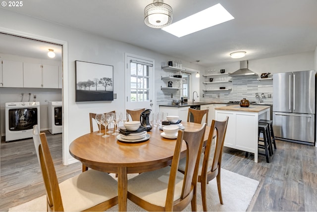 dining area with light wood-style floors, independent washer and dryer, and a skylight
