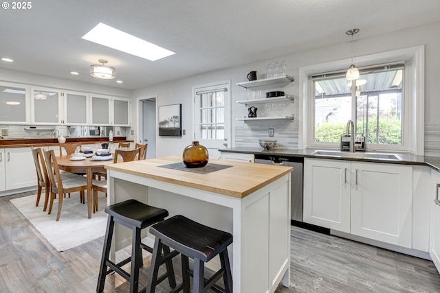 kitchen with light wood-style floors, a kitchen bar, a sink, wood counters, and a skylight