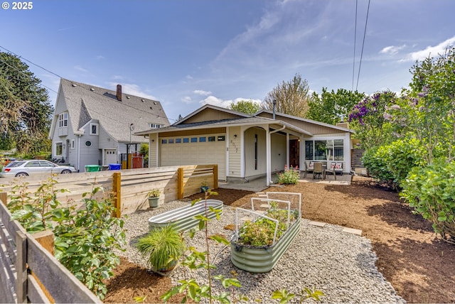 view of front facade featuring an attached garage, fence, and a vegetable garden