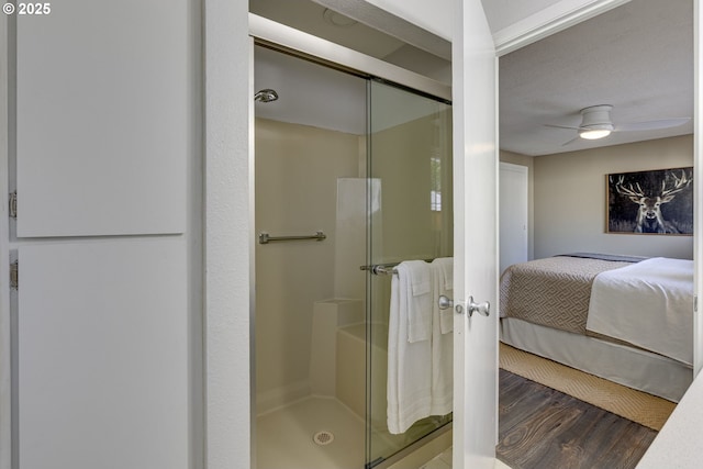 ensuite bathroom with ceiling fan, a stall shower, wood finished floors, and connected bathroom