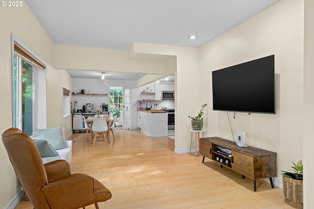 living room with recessed lighting, baseboards, and light wood-style flooring