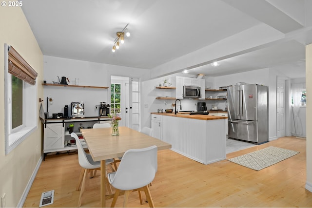 kitchen with white cabinets, open shelves, appliances with stainless steel finishes, butcher block countertops, and light wood-style flooring