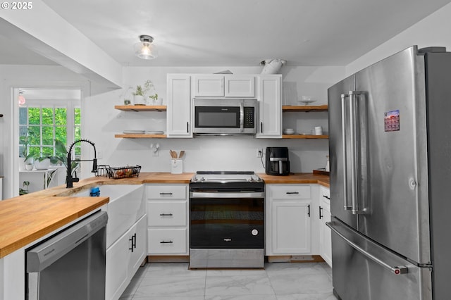 kitchen with stainless steel appliances, open shelves, wooden counters, and a sink