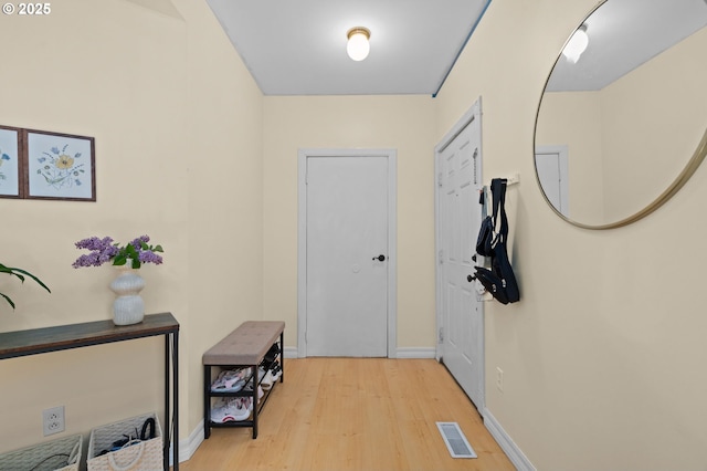 doorway with baseboards, visible vents, and wood finished floors