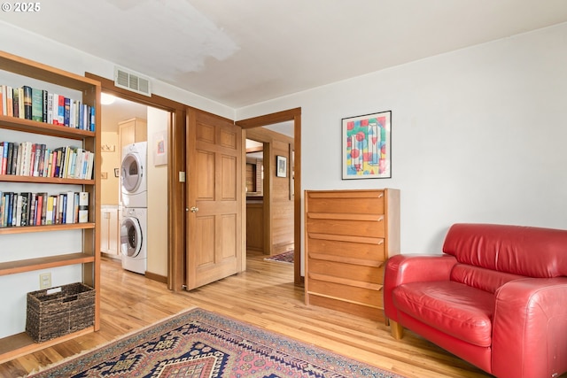 sitting room featuring visible vents, light wood finished floors, and stacked washer and clothes dryer