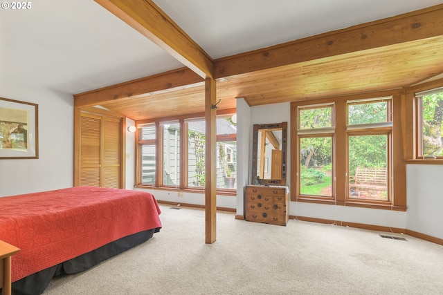 bedroom featuring carpet floors, baseboards, beamed ceiling, and visible vents