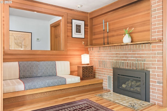 living area featuring wooden walls, a fireplace, and wood finished floors