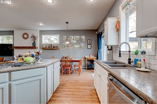 kitchen featuring sink, light hardwood / wood-style flooring, stainless steel appliances, white cabinets, and decorative light fixtures