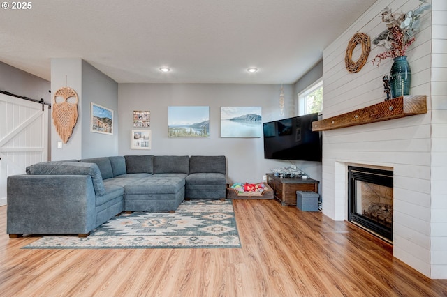 living room featuring a large fireplace, wood-type flooring, and a barn door