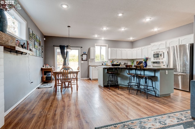 kitchen with a breakfast bar area, a center island, appliances with stainless steel finishes, decorative backsplash, and white cabinets