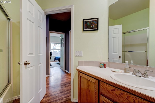 bathroom featuring hardwood / wood-style flooring, vanity, and shower / bath combination with glass door