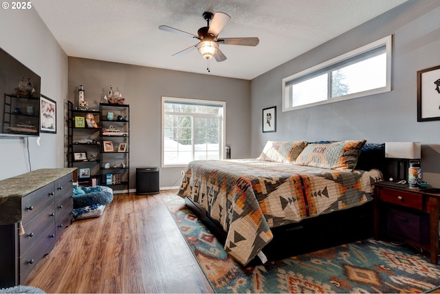 bedroom with ceiling fan, light hardwood / wood-style flooring, and a textured ceiling