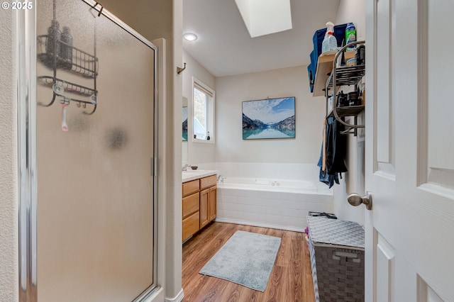 bathroom featuring a skylight, vanity, wood-type flooring, and plus walk in shower