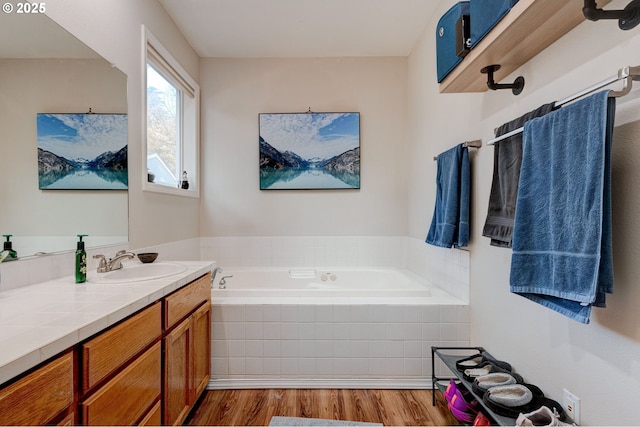 bathroom featuring vanity, hardwood / wood-style flooring, and tiled bath