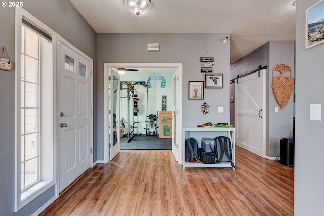 entrance foyer featuring light hardwood / wood-style floors, a barn door, and a textured ceiling