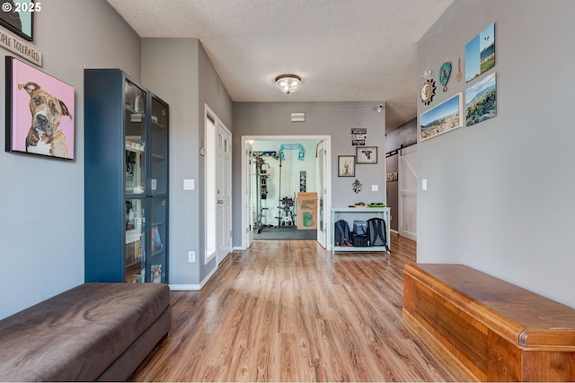 corridor with hardwood / wood-style flooring, a barn door, and a textured ceiling