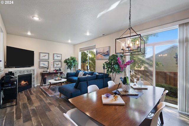 dining space with a chandelier, dark hardwood / wood-style floors, a tiled fireplace, and a textured ceiling