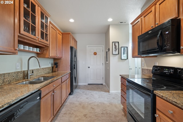 kitchen with sink, light stone counters, and black appliances