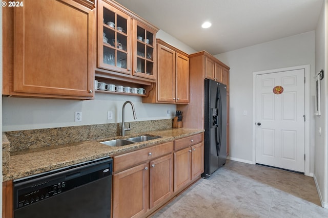 kitchen featuring light stone countertops, sink, and black appliances